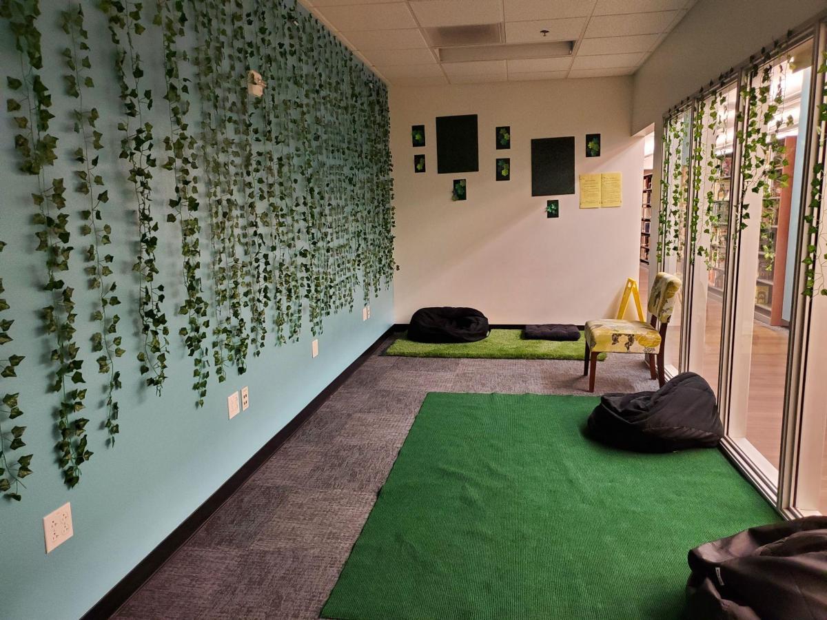  room with green rug, a piece of faux outdoor green grass, vines on the walls, chairs and bean bags